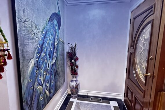 Entryway interior with decorative peacock wall art, modern ceiling chandelier, crown molding, and custom front door.