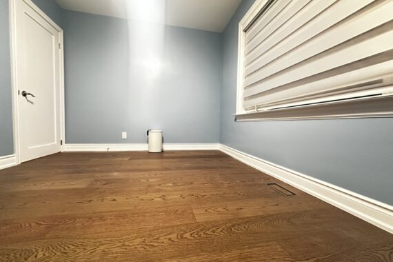 Finished room with hardwood flooring, light blue painted walls, white baseboards, window blinds, and a closed interior door.
