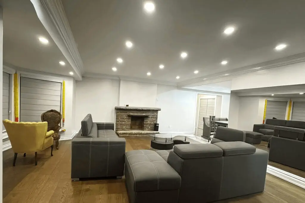 Professional interior renovation by ASM Constructions and Renovations showcasing custom lighting, updated flooring, and a classic brick fireplace.