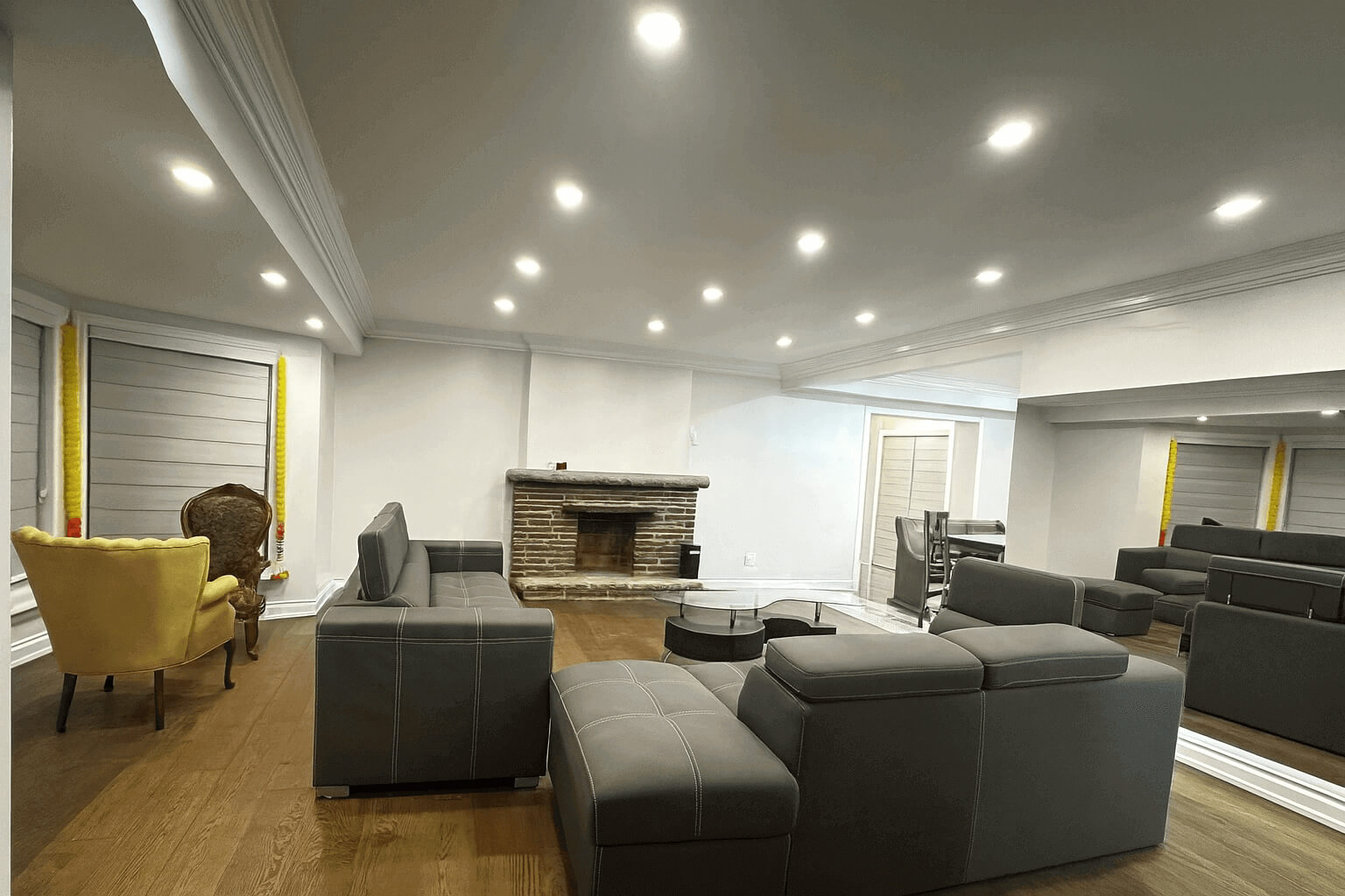 Professional interior renovation by ASM Constructions and Renovations showcasing custom lighting, updated flooring, and a classic brick fireplace.